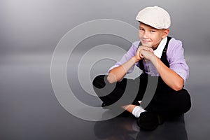 Old fashioned boy sitting on gray background