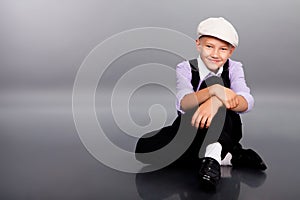 Old fashioned boy sitting on gray background