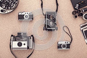 Old fashioned cameras on wooden cork table in te darkroom. View from above