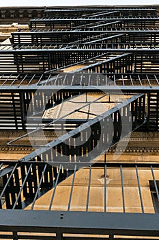 Old-fashioned cast-iron fire-escape on the outside of an apartment building in New York City`s Harlem neighborhood, NYC