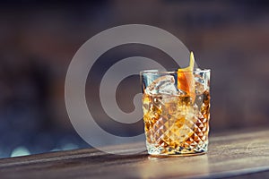 Old fashioned classic cocktail drink in crystal glass on bar counter.