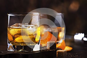 Old fashioned cocktail with bourbon, cane sugar, orange slice, cherry and orange peel garnish, vintage wood table, copy space