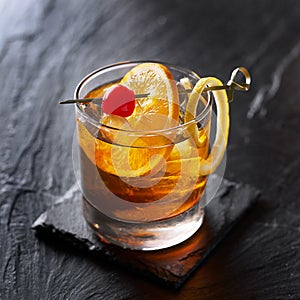 Old fashioned cocktail garnished with cherry, orange and lemon peel