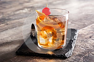 Old fashioned cocktail with orange and cherry on wood