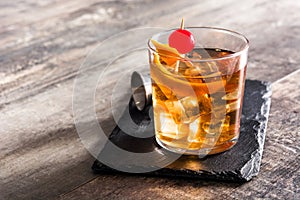 Old fashioned cocktail with orange and cherry on wood photo