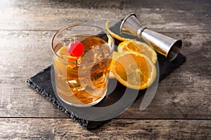 Old fashioned cocktail with orange and cherry on wooden table
