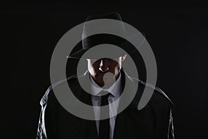 Old fashioned detective in hat on dark background