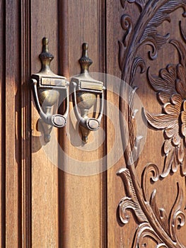 Old fashioned door knocker with carved door