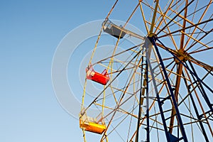 Old-fashioned ferris wheel with yellow and red seat