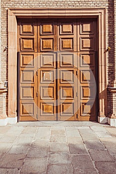 Old fashioned front double doors, all in dark brown colors. Beautiful stone door platband and wooden panels on doors