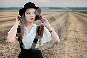 Old fashioned girl with suspenders and hat, wolk on field at sunset time photo