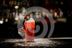 Old-fashioned glass with cold red drink decorated with Christmas tree toy and chocolate candy man