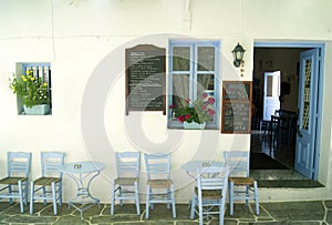 An old fashioned Greek cafe in a square on the island of Folegandros. Blue painted tables and chairs.