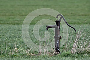 Old fashioned hand water pump in a field close to Oss, Netherlands