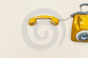 Old fashioned handset on beige color background. Modern retro style of rotary telephone.