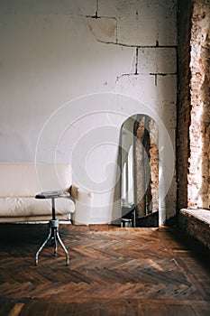 Old fashioned interior big wooden window and mirror, white sofa in old vintage living room with brick walls