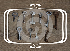 Old fashioned keys on wooden aged background with frame concept