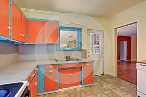 Old fashioned kitchen interior with orange and blue cabinets.