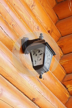 Old-fashioned lantern on logs wall