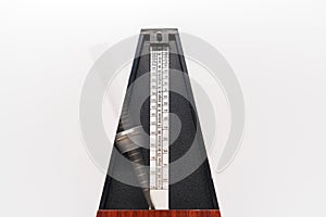 Old fashioned metronome with blurred arm indicating motion isolated on a white background