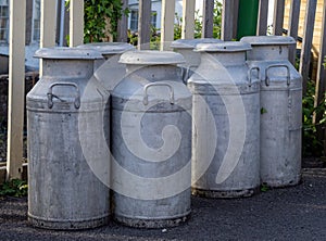 Old fashioned milk churns by fence. Vintage agriculture. photo