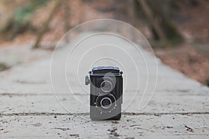 Old-fashioned photography camera on wooden way in autumn forest