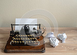 Old antique portable typewriter with screwed up paper on desk photo
