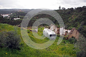 Old-fashioned residential trailer parked on the green besides the ruined rural house, near Belver, Portugal