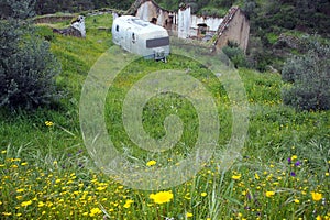 Old-fashioned residential trailer parked on the green besides the ruined rural house, near Belver, Portugal