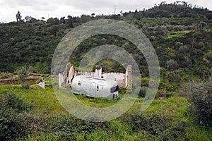 Old-fashioned residential trailer parked on the green besides the ruined rural house, near Belver, Portugal