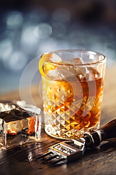 Old fashioned rum drink on ice with orange zest garnish