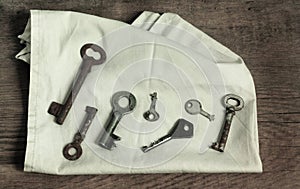 Old fashioned rusty keys on grey napkin and wooden surface