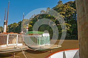 Old fashioned steam boats moored alongside waterfront pier on Mahurangi River