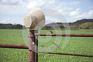 Old fashioned straw bonnet on fence post in Texas Hill Country