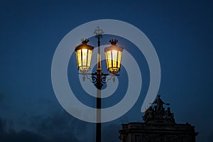 Old fashioned street lamp at night. Magic lamp with a warm yellow light in the city twilight