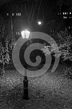 Old-fashioned street lamp in a public park at night on Manhattan`s Upper East Side, New York City, in black & white