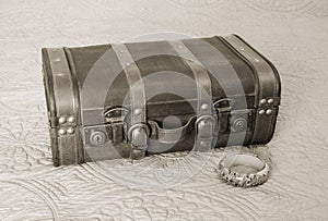 Old fashioned suitcase and floral bangle bracelet in sepia tone, vintage travel concept
