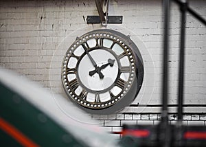 Old fashioned vintage big industry factory clock hanging with roman numerals in abandoned building no workers.