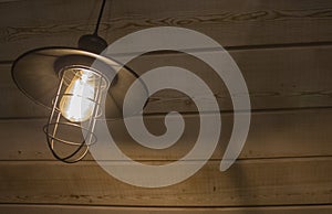 Old fashioned vintage lantern lamp burning with a soft glow light in an antique rustic country barn with aged wood wall
