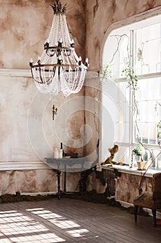 Old fashioned vintage room corner with black table and candles. Dirty walls covered with fern, big crystal ceiling light