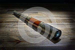 Old fashioned, vintage telescope on a rustic wooden background.