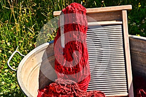 An old fashioned washing trougth filled with dyed and washed strings and ropes of red wool