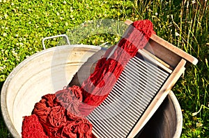 An old fashioned washing trougth filled with dyed and washed strings and ropes of red wool