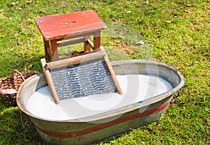 An old fashioned washing trougth a vintage child chair, and wooden vessels to bring water