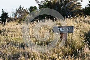 Old-fashioned weathered sign for track in a field