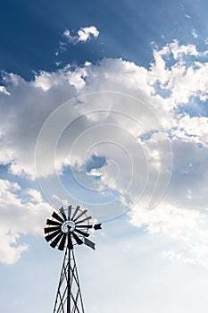 Old-fashioned wind pump against blue sky with white clouds