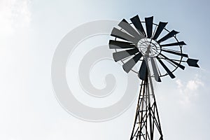 Old-fashioned wind pump against pale blue sky