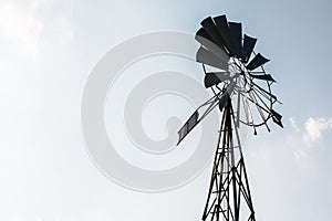 Old-fashioned wind pump against pale blue sky