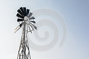 Old-fashioned wind pump against pale blue sky