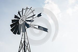 Old-fashioned wind pump against pale blue sky with white clouds